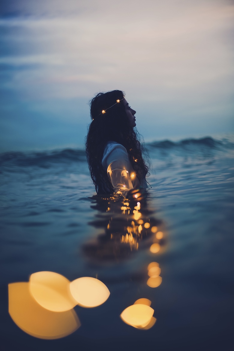 Girl in the sea in the dusk time with lights around